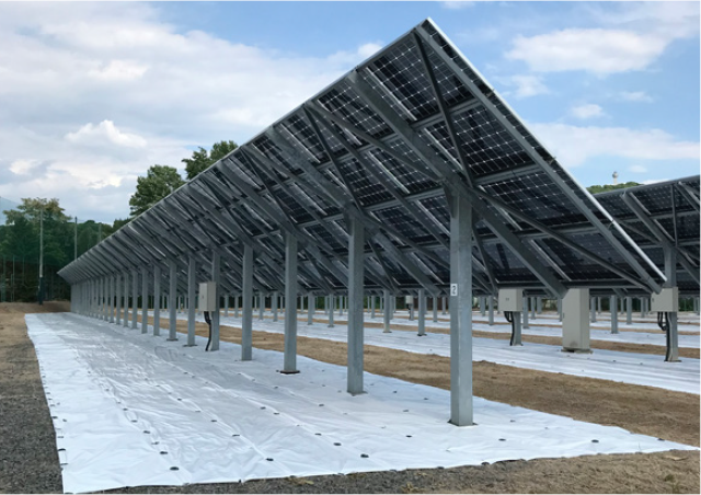 A panoramic view of a mega-solar power plant, featuring rows of solar panels mounted on ground-mounted racks