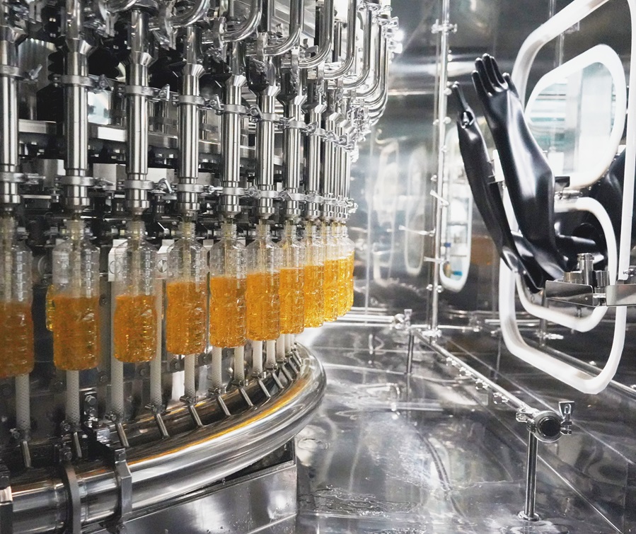 Automated aseptic filler machine evenly filling PET bottles in a sterile production line