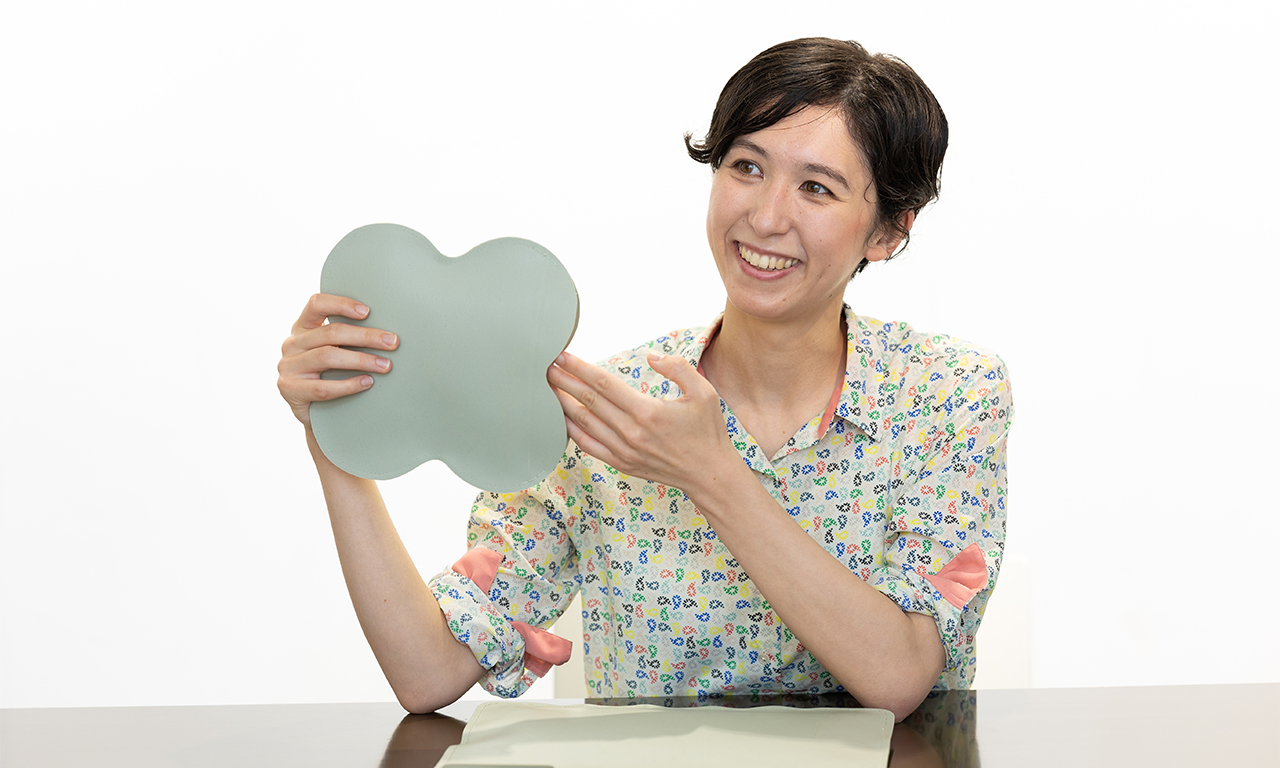 Ms. Suzuki talking while holding a four-leaf clover shape of reusable packet for delivery